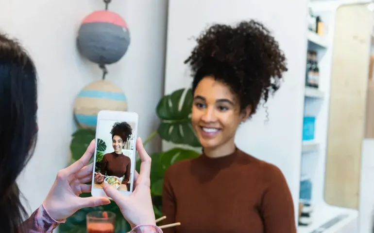crop-woman-taking-photo-of-friend-in-restaurant